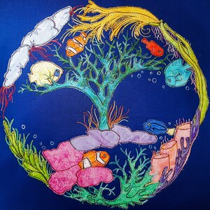 May include: A blue fabric wall hanging with colorful embroidered fish, coral, and seaweed. The design features a central tree-like structure with a yellow, feathery top.