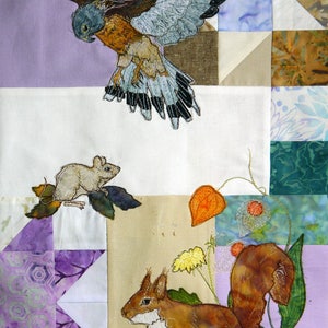 Puede incluir: Una colcha de retazos colorida con imágenes bordadas de un pájaro, un ratón, una ardilla y flores. La colcha está hecha de varias telas, incluyendo morado, verde, marrón y blanco.