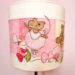Könnte beinhalten: Ein rosa-weißer Lampenschirm mit Patchwork-Design, das eine Ballerina-Maus und rosa Blumen zeigt. Der Lampenschirm ist aus Stoff und hat einen weißen Rand.