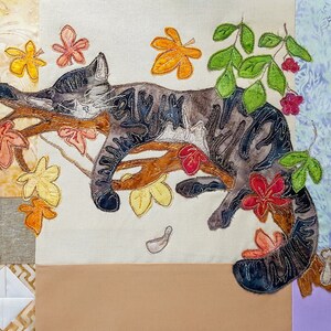 Peut inclure: Un chat gris et noir avec des marques blanches dort sur une branche avec des feuilles brunes et des fleurs rouges. Le chat est entouré de feuilles vertes et de branches brunes.