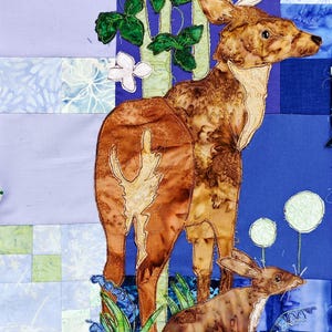 May include: A fabric art piece featuring a deer and a rabbit in a forest scene. The deer has large antlers and is brown with tan accents. The rabbit is brown. The background is a patchwork of blue, green, and white fabrics.