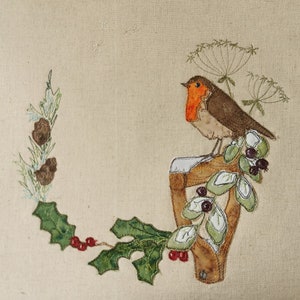 Könnte beinhalten: Ein Rotkehlchen sitzt auf einer Holzkonstruktion mit Stechpalme und Beeren. Das Rotkehlchen ist braun mit einer roten Brust und von grünen Blättern umgeben.