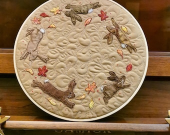 Finished Textile Art mounted I0" hoop running rabbits on tan cotton