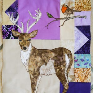 May include: A quilt block with a brown and white deer, a red robin on a branch, and a variety of purple, green, and brown fabric squares.