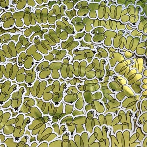 May include: A collection of gold-colored stickers with the word "STINKY" in a stylized, cursive font. The word is outlined in black and adorned with small star accents. The stickers have a glossy finish and are scattered across the image.