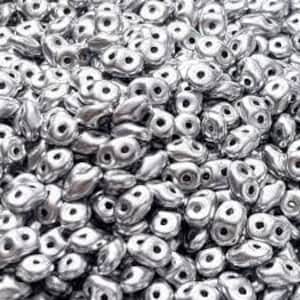 May include: A large pile of silver-coloured glass beads. The beads are small and have a teardrop shape with a hole in the centre.