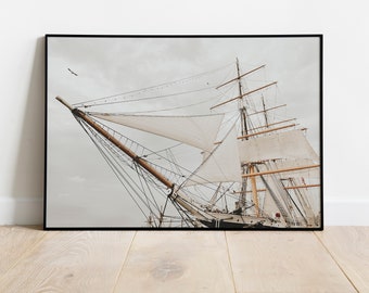 May include: A close-up of a large sailing ship with white sails against a cloudy sky. The ship's masts and rigging are visible, and the sails are billowing in the wind.