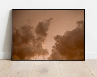 Peut inclure: Une photographie encadrée d'un ciel nuageux avec une palette de couleurs chaudes et brunes. Les nuages sont moelleux et semblent se déplacer à travers le ciel.