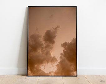 Peut inclure: Une photographie encadrée d'un ciel nuageux avec une palette de couleurs chaudes et brunes. Les nuages sont moelleux et semblent se déplacer à travers le ciel.