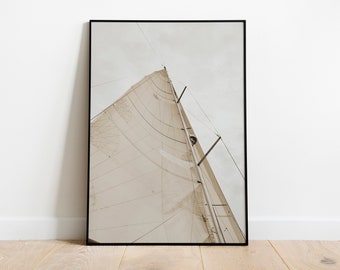 May include: A close-up view of a white sail billowing in the wind, with the sky visible above. The sail is made of a textured fabric and is attached to a mast with ropes.