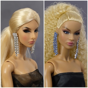 May include: Two fashion dolls with long blonde hair wearing black strapless dresses and long dangling earrings. One doll has silver earrings and the other has blue earrings.