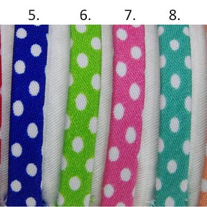 May include: Thirteen samples of white cotton ribbon with different colored polka dots. The colors are red, blue, green, pink, turquoise, orange, gray, yellow, black, and white.