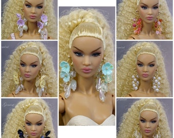 May include: Nine images of a doll with blonde hair wearing different pairs of statement earrings. The earrings are made of various materials, including beads, crystals, and flowers.