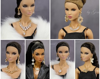 May include: Six different dolls with various hairstyles and outfits are wearing gold necklaces and earrings with clear gemstones. The dolls are wearing black dresses, a black leather jacket, and a white fur coat.