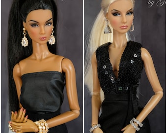 May include: Two fashion dolls wearing black dresses and jewelry. The doll on the left has long black hair pulled back in a ponytail and is wearing a strapless dress. The doll on the right has long blonde hair and is wearing a sleeveless dress with sequins. Both dolls are wearing earrings and bracelets.