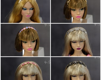 May include: Six different headbands for dolls, each with a different design. The headbands are made of various materials, including metal, plastic, and fabric. The headbands are all in different colors, including gold, silver, pink, blue, and white.