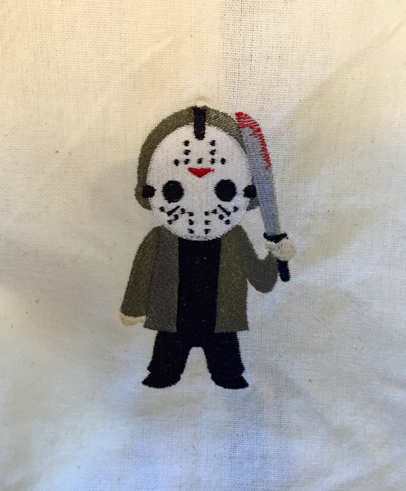 May include: Embroidered patch featuring a cartoon version of Jason Voorhees from the Friday the 13th horror film series. The patch shows Jason wearing his signature hockey mask and holding a bloody machete. The patch is on a white background.