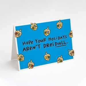 May include: A blue card with a Hanukkah greeting that says "Hope your holidays aren't dreidull." The card is decorated with yellow dreidels with Hebrew letters on them.