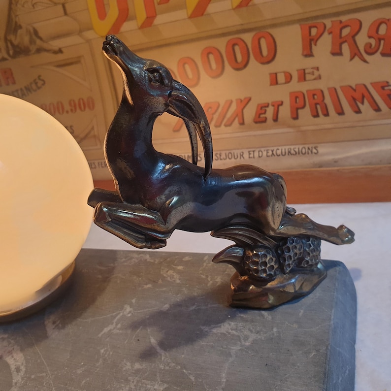 May include: A bronze sculpture of a leaping gazelle, with a textured base, on a gray marble surface. The sculpture is a decorative accent for a home or office.