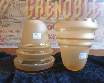 May include: Two frosted glass lampshades, one with a bell shape and the other with a cylindrical shape. Both shades have a gold tint and are labeled with "AD 10".