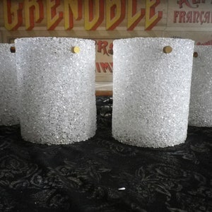 May include: Five clear glass cylinder lampshades with a textured surface and a gold metal top.