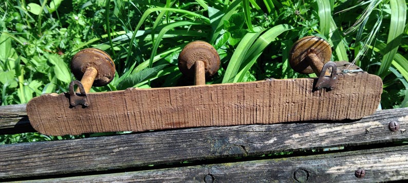 May include: A wooden shelf with three round, brown, wooden knobs. The shelf is made of rough-hewn wood and has a rustic look.