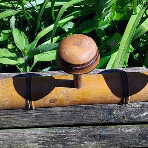 May include: A wooden coat rack with three hooks. The hooks are made of wood and have a dark brown finish. The rack is made of bamboo and has a natural finish.