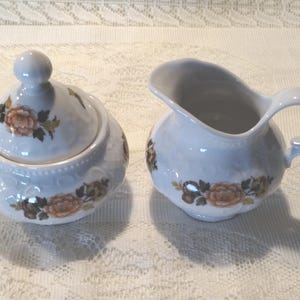 May include: A handmade, wooden serving tray with a natural finish. The tray features a rectangular shape with rounded corners and raised edges. It has two cut-out handles on either side for easy carrying. The wood grain is visible throughout.