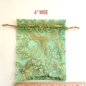 K&ouml;nnte beinhalten: Eine gr&uuml;ne, durchsichtige Kordeltasche mit goldenem Blumenmuster. Die Tasche ist 4 Zoll breit.
