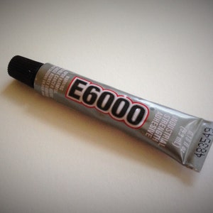 May include: A silver tube of E6000 industrial strength adhesive with a black cap. The tube is labeled with the product name, size, and warnings.