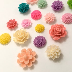 Könnte beinhalten: Sortiment an bunten Plastikblumenverzierungen in verschiedenen Formen und Größen, darunter Rosen, Gänseblümchen und Nelken.