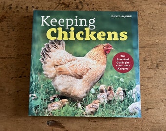 May include: Book cover with the title "Keeping Chickens" in yellow letters. The cover features a brown hen with chicks in a grassy field. The subtitle is "The Essential Guide for First-time Keepers".