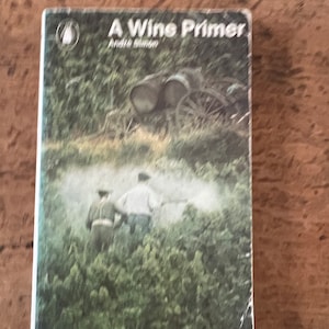 May include: A book titled "A Wine Primer" by Andre Simon. The cover features a vintage photograph of a vineyard with two people working in the field and a wagon in the background.