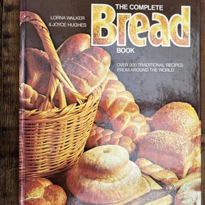 May include: A cookbook titled "The Complete Bread Book" with a brown cover featuring a basket of bread and various baked loaves. The cover text includes the authors' names and states "Over 200 Traditional Recipes From Around The World".