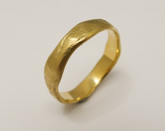 May include: A simple gold wedding band with a textured finish.