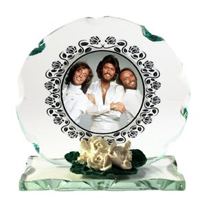 Könnte beinhalten: Ein Glasbildrahmen mit weißem Hintergrund und einem schwarz-weißen Blumendesign. Der Rahmen hat ein Foto von drei Männern in weißen Hemden. Der Rahmen steht auf einem Glassockel mit einer weißen Rosenverzierung.