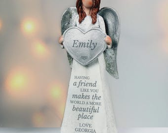 May include: A white angel figurine with silver wings and brown hair, holding a heart-shaped plaque that reads "Emily." The angel's dress has the inscription "HAVING a friend LIKE YOU makes the WORLD A MORE beautiful place LOVE GEORGIA."