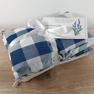 K&ouml;nnte beinhalten: Ein Set aus drei blauen und wei&szlig;en karierten W&auml;rme- und K&auml;ltepacks, die mit einem wei&szlig;en Band zusammengebunden sind. Die Packs sind mit "Large Heat & Cold Pack" beschriftet und zeigen eine Lavendel-Illustration.