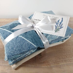 K&ouml;nnte beinhalten: Ein blaues und wei&szlig; gemustertes W&auml;rmekissen, das mit einem wei&szlig;en Band umwickelt und mit einer Schleife gebunden ist. Das W&auml;rmekissen ist mit einer wei&szlig;en Karte verpackt, auf der "Larger Heat Pack" und "Tanessa Rae Designs" steht.