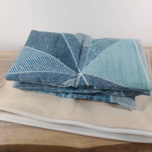 K&ouml;nnte beinhalten: Ein blaues und wei&szlig;es geometrisches Stoff-Augenkissen mit einer Rei&szlig;verschluss-Tasche aus beigefarbener Leinwand.