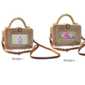 May include: Two woven rattan handbags with brown leather straps and handles. Design 1 features a green and white checkered rectangle with pink tulips. Design 2 has a green rectangle with pink and blue flowers.