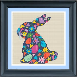 May include: A colorful cross-stitch pattern of an Easter bunny filled with flowers, eggs, and hearts. The bunny is outlined in black and the background is a light beige.