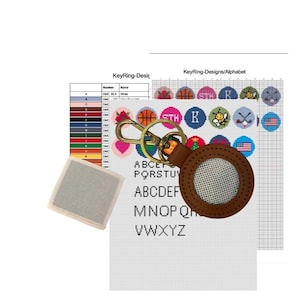 May include: A brown leather keychain with a gold-colored clasp, a white mesh center, and a cross-stitch alphabet chart. The chart includes color swatches and various cross-stitch designs.