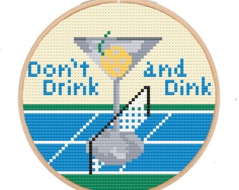May include: A round embroidery hoop with a white background and a blue and green tennis court design. The text "Don't Drink and Dink" is written in black letters. A martini glass with a yellow lemon wedge is in the center of the hoop.