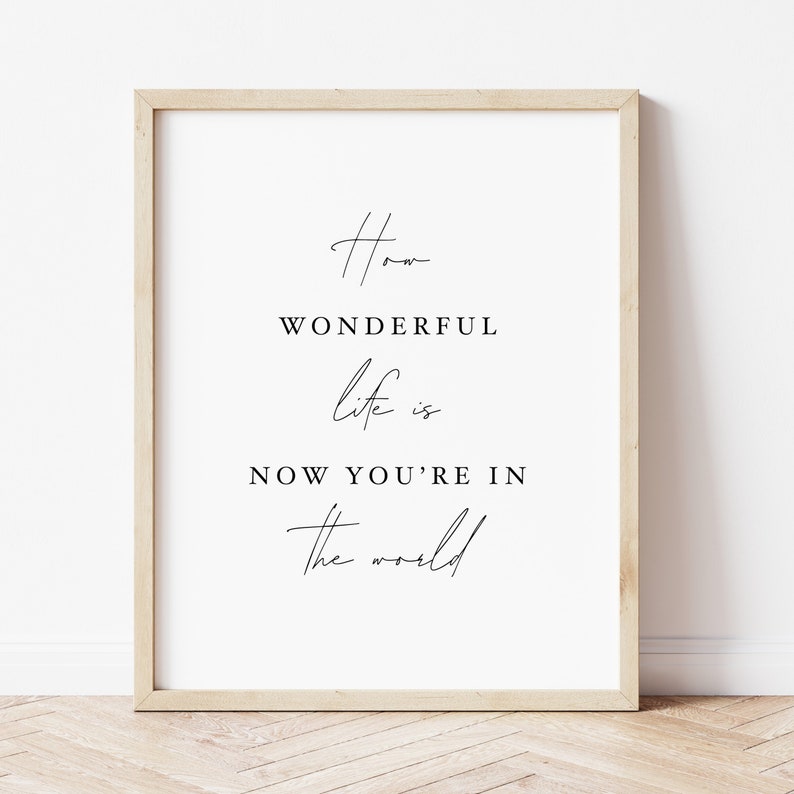 Pode incluir: Uma impress&atilde;o emoldurada com o texto "How wonderful life is now you're in the world" em uma fonte preta simples em um fundo branco.