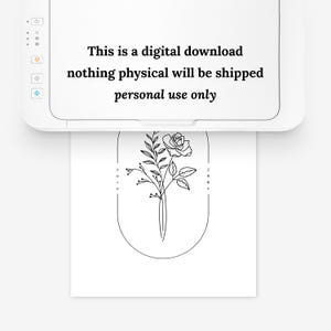 May include: A black and white line drawing of a rose with leaves inside an oval frame. The words "rose" and "june" are written vertically on either side of the frame.