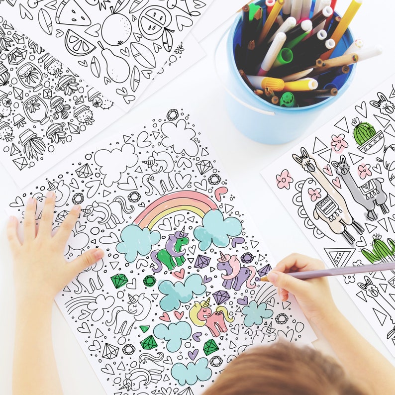 May include: A child colors a black and white coloring page with a rainbow, clouds, hearts, and unicorns. The child is using a gray colored pencil to color the page.