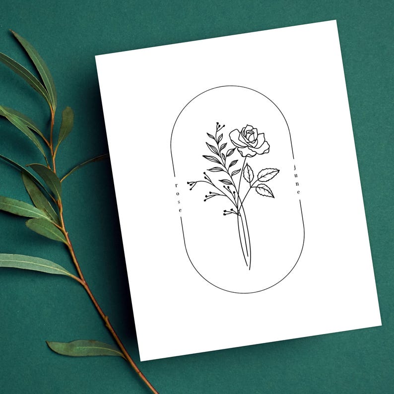 May include: A black and white line drawing of a rose with leaves and buds inside an oval frame. The text "rose" and "june" are written vertically on either side of the frame.