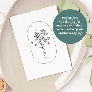 May include: A black and white line drawing of a rose with leaves inside an oval frame. The text "June" is written vertically on the right side of the frame. The text "You are" is written vertically on the left side of the frame.
