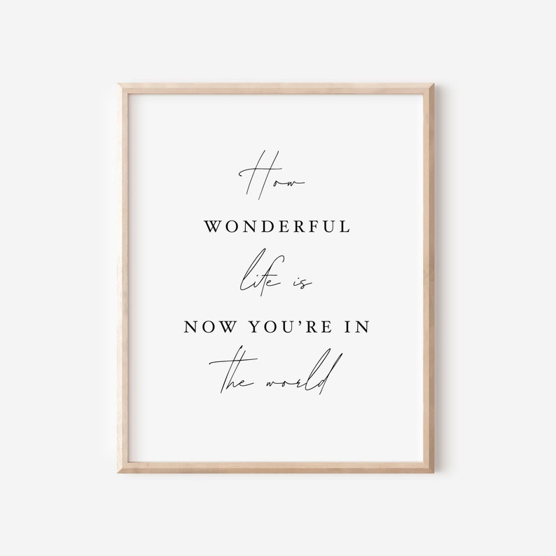 Pode incluir: Uma impress&atilde;o emoldurada com o texto "How wonderful life is now you're in the world" em uma fonte preta minimalista.